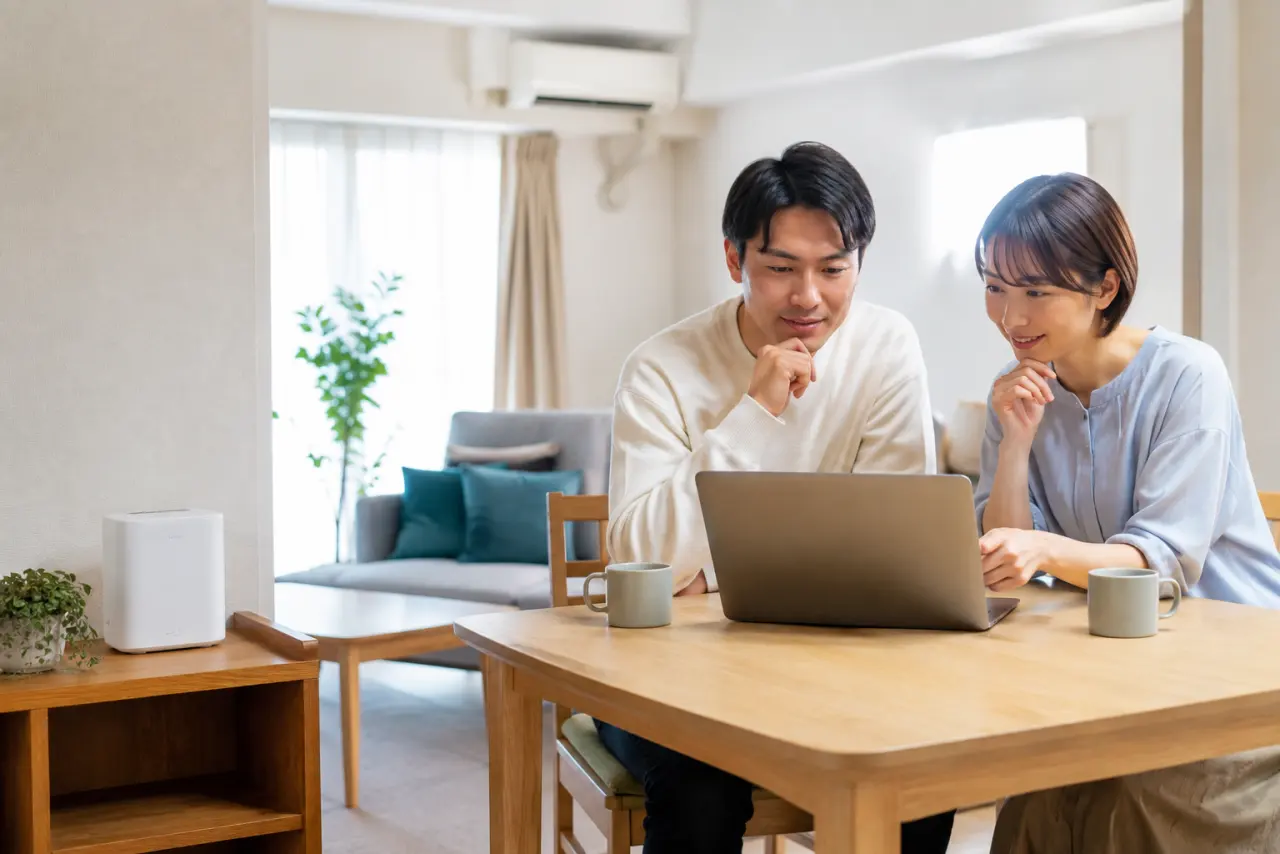 明るいリビングでパソコンを見ながら通信プランを検討する二人